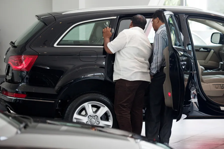 Customers inspect a VW Audi Q7 SUV&nbsp;on display inside a dealership in New Delhi.
