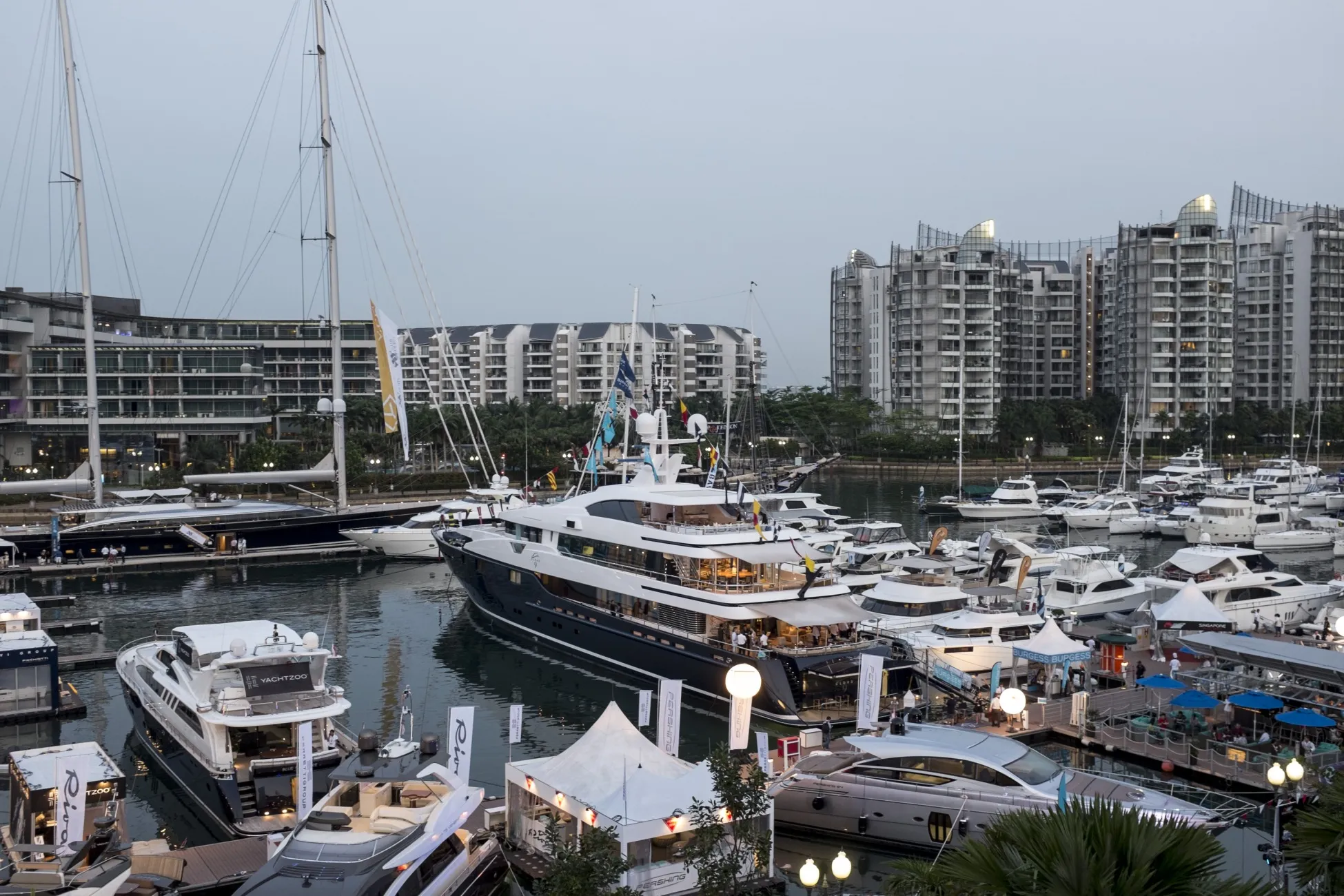 Luxury yachts sit moored at the Singapore Yacht Show in front of residential buildings of Sentosa Cove in Singapore, on Thursday, April 10, 2014. The yacht show runs through April 13.