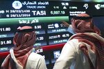 Visitors stand and watch stock movements displayed inside the Saudi Stock Exchange.