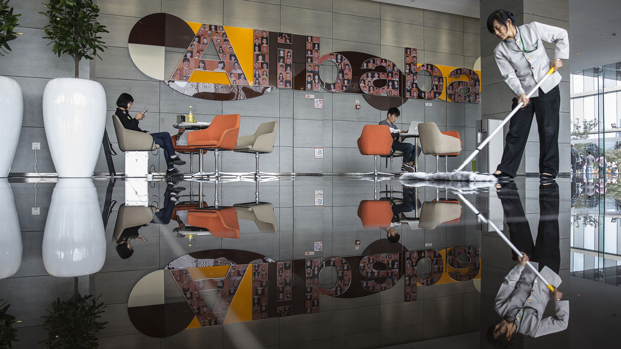 An employee mops the floor in a building lobby at the Alibaba Group Holding Ltd. headquarters in Hangzhou, China, on Tuesday, Oct. 13, 2015. Alibaba's bet on data technology is driving greater investment in areas including ways to protect user privacy as it battles Amazon.com Inc. for customers globally.
