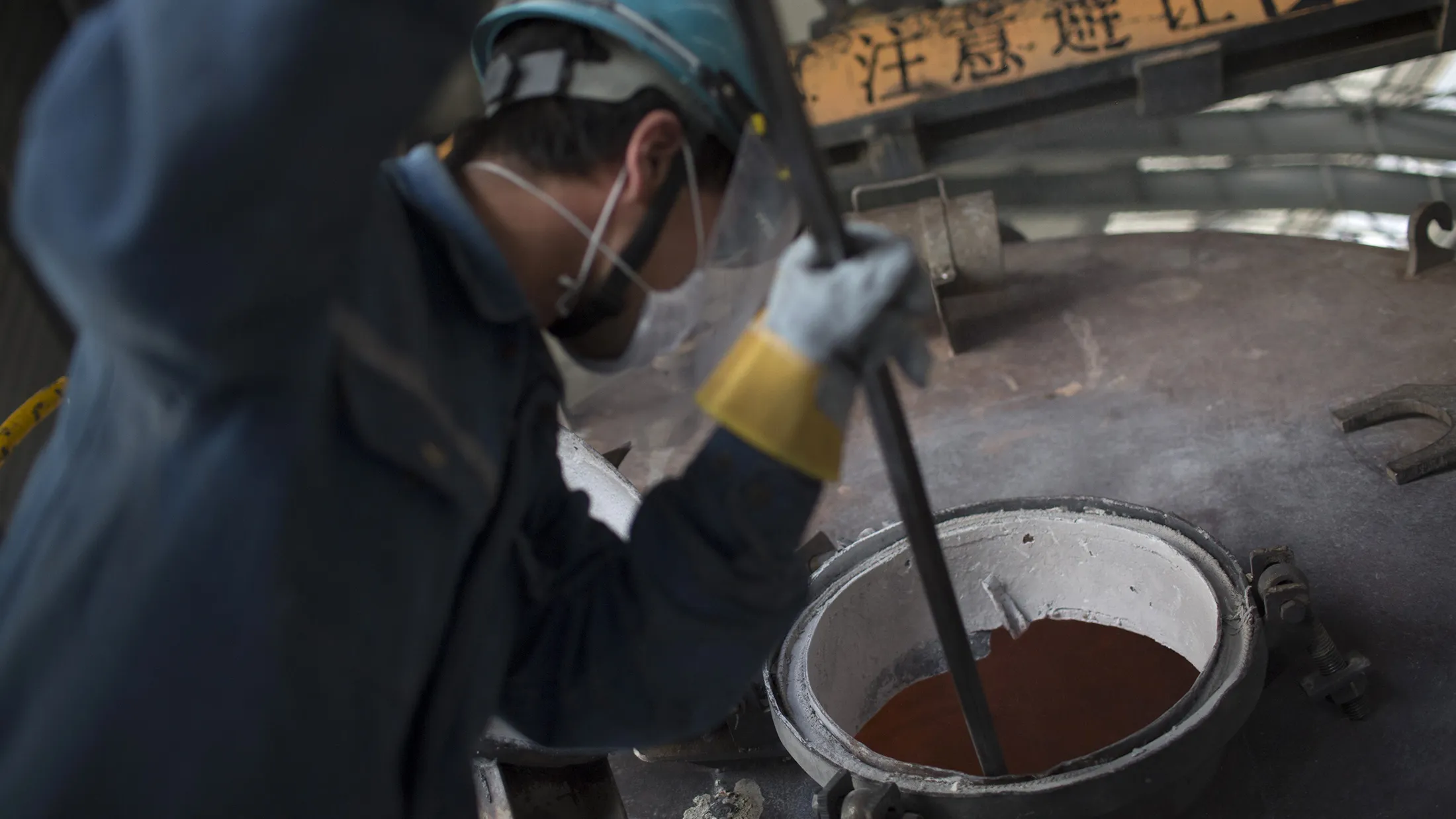 An employee cleans residue from a container at an aluminum smelting facility in Zouping, China.
