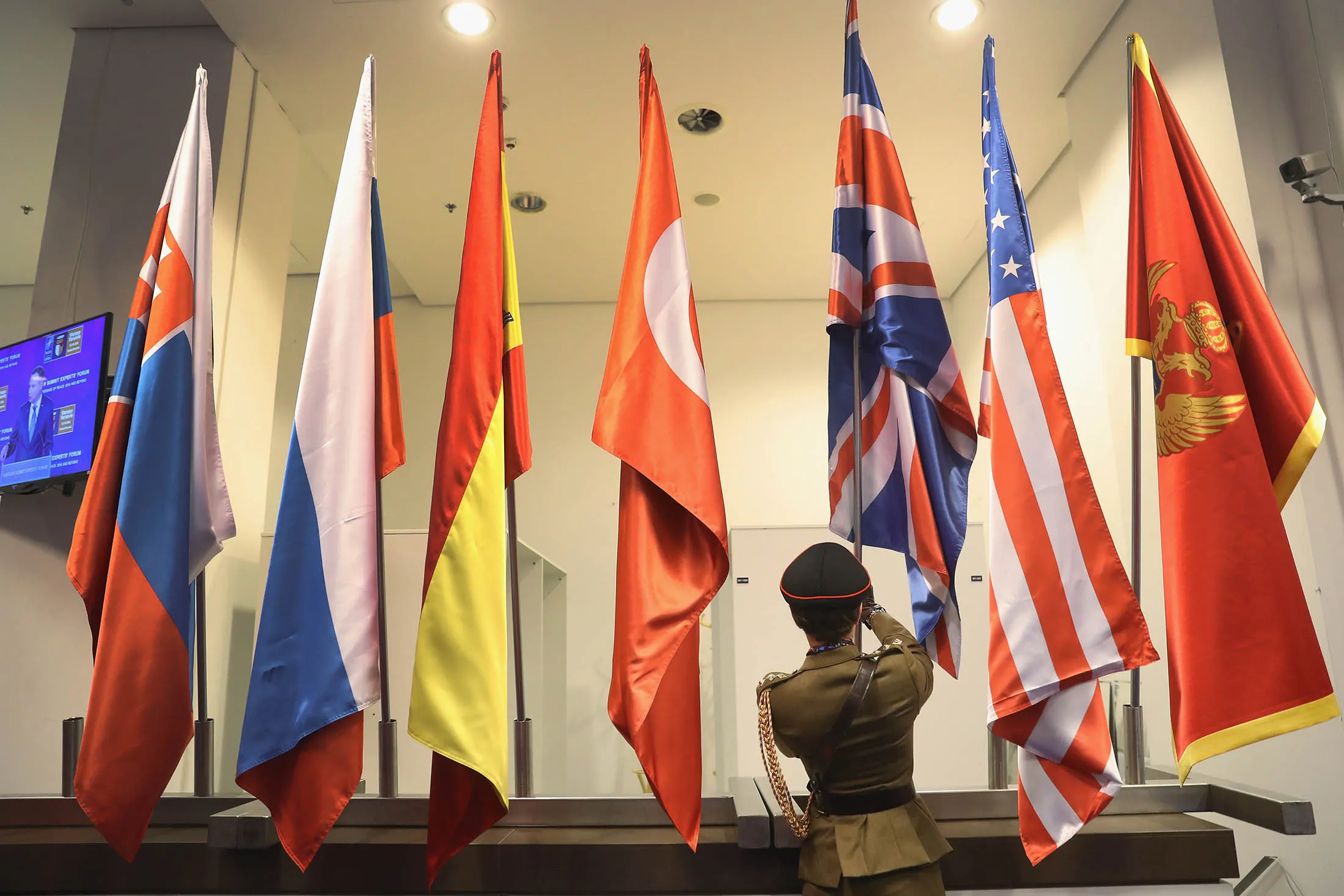 A flag-bearer places the flag of the U.K. among flags of other NATO member states at the PGE National Stadium, site of the NATO summit, on July 8, 2016, in Warsaw.
