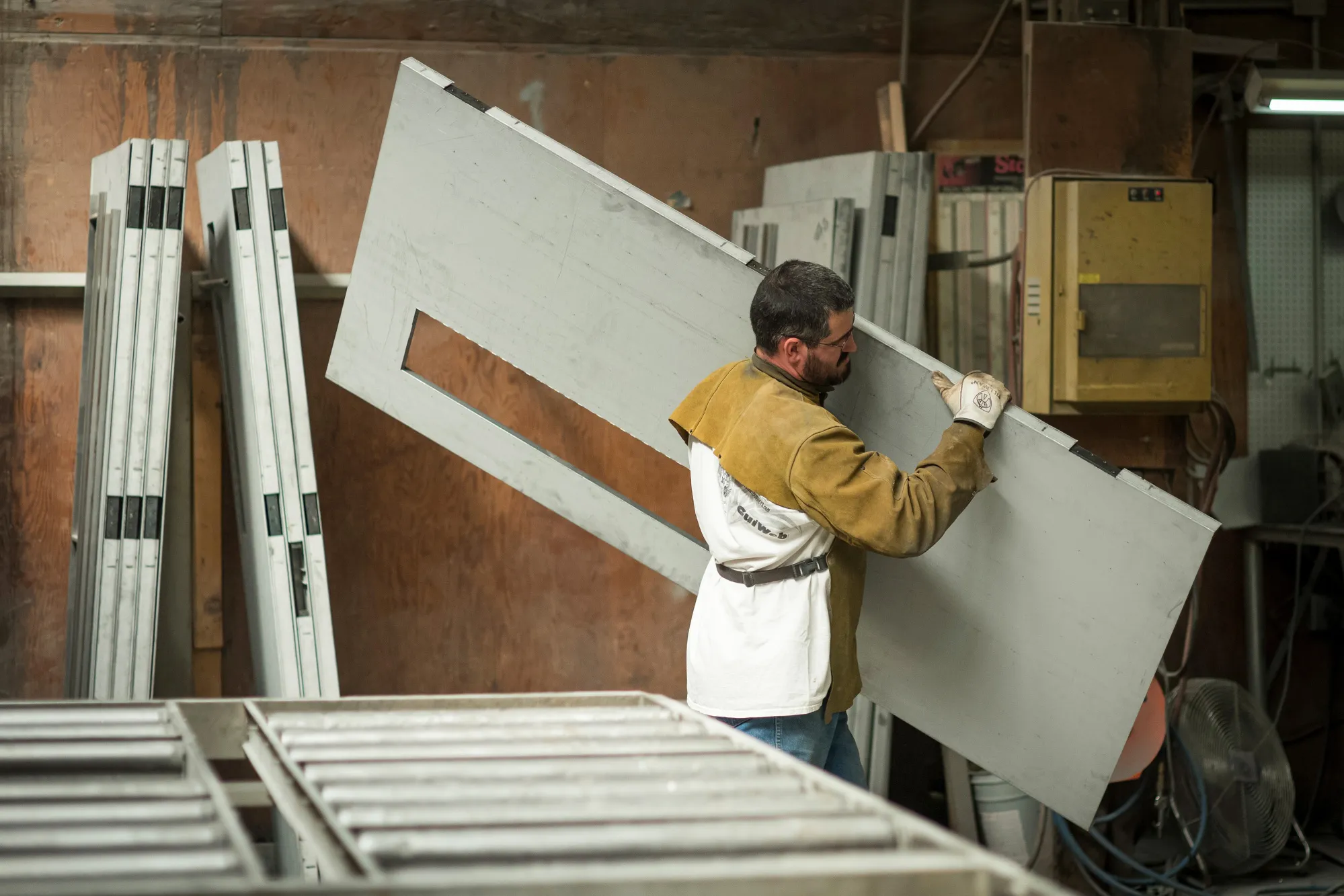 A worker carries a metal door during production at a manufacturing facility in Sacramento, California.