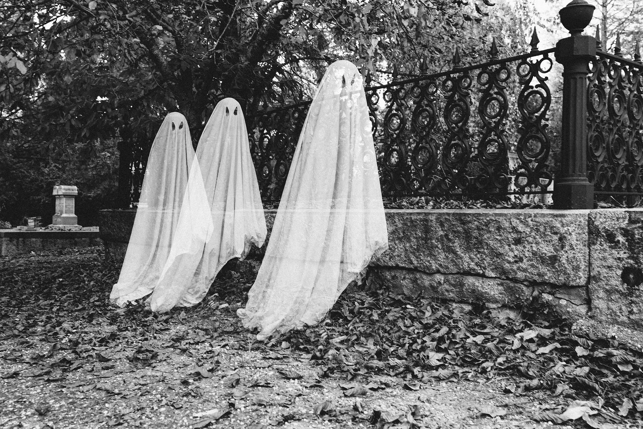Double exposure of boys in ghost costumes at cemetery during Halloween