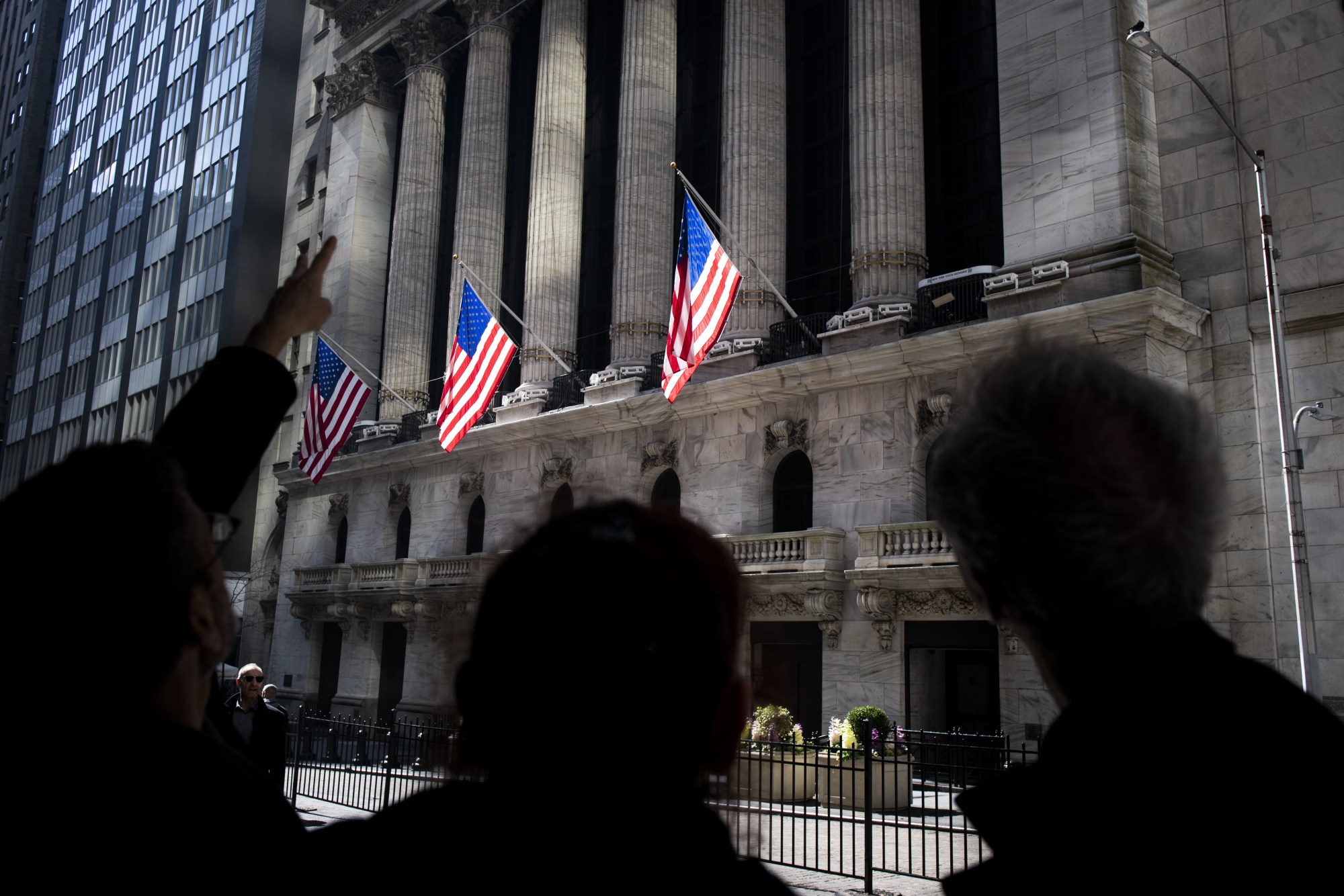 Pedestrians stand in front of the New York Stock Exchange on March 13.