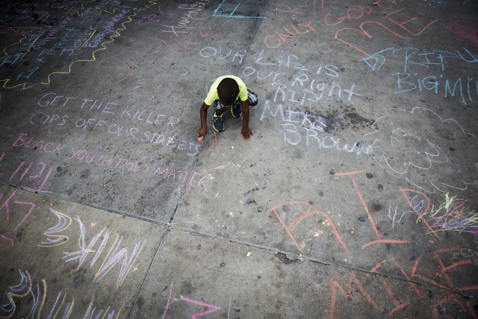 Young boy chalks a sidewalk following the police killing of Michael Brown in Ferguson, Missouri. 
