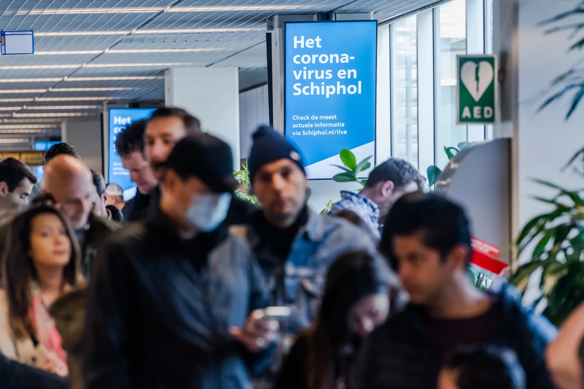 A sign advertising coronavirus information hangs above travelers at Schiphol Airport in Amsterdam on March 14.
