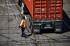 A worker checks a semi-truck chassis at the APM shipping terminal in the Port of Los Angeles in Los Angeles, California, U.S., on Tuesday, May 7, 2019. The terminal is planning to replace diesel trucks and human workers. It has already ordered an electric, automated carrier from Finnish manufacturer Kalmar, part of the Cargotec Corp., that can fulfill the functions of three kinds of manned diesel vehicles: a crane, top-loader and truck.