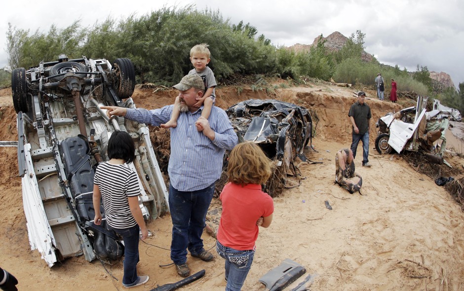 Russ Cook and his family stands next to severely damage vehicles swept away during a flash flood Tuesday, September 15, 2015, in Hildale, Utah.