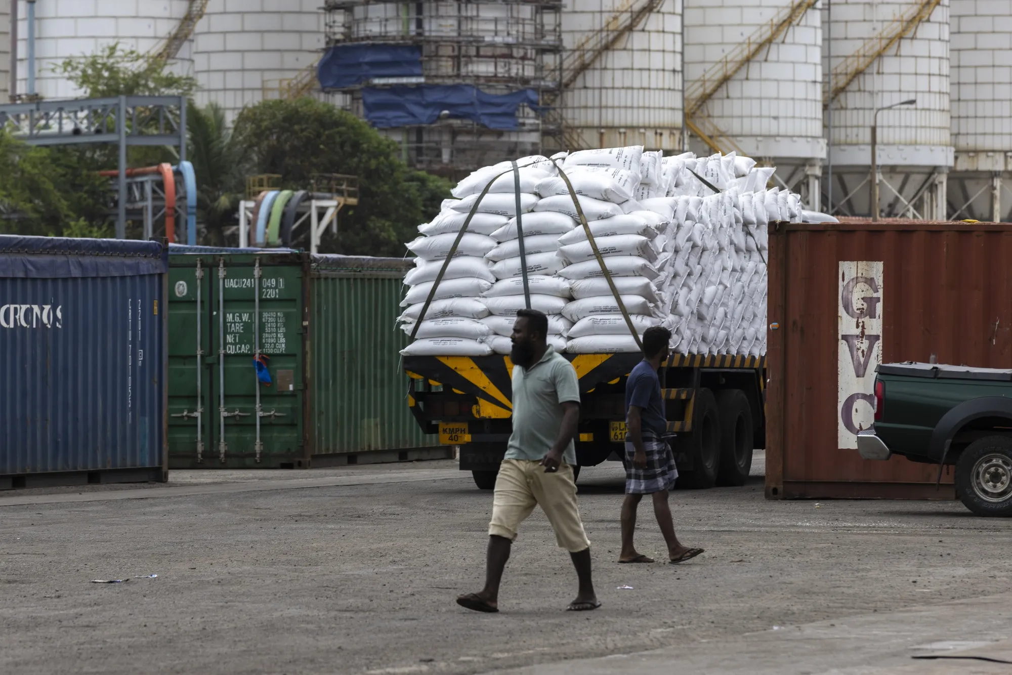 Workers walk past a truck carrying sacks of fertilizer at Port of Colombo.