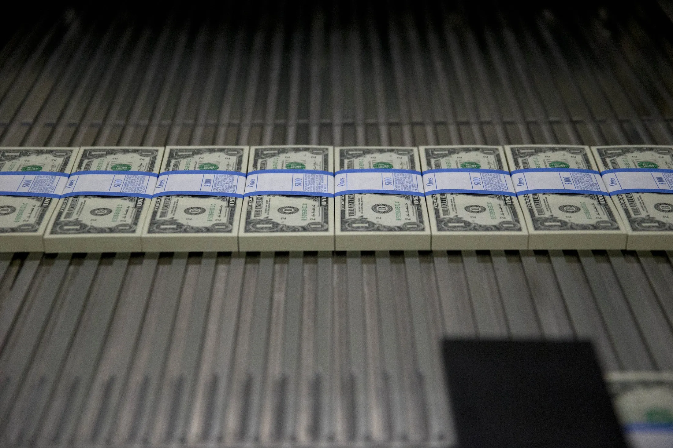 One dollar notes travel through a large examining packaging equipment machine