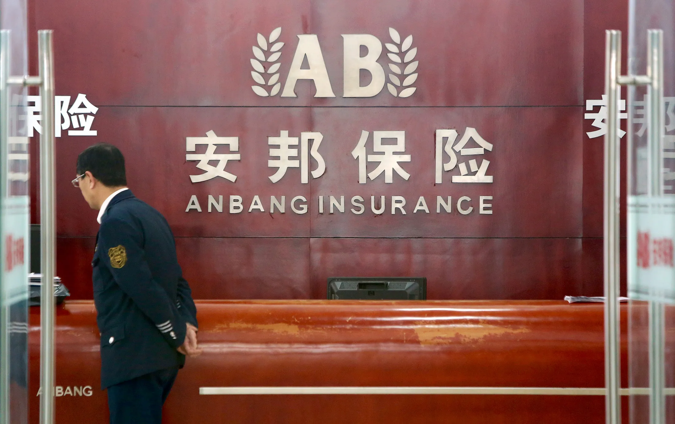 A security guard walks past the front desk at a branch of Anbang Insurance in Shanghai.
