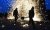 TOPSHOT - This photo taken on February 18, 2019 shows Chinese blacksmith carrying a bucket of molten steel as a shower of sparks descends behind them, on the eve of the Lantern Festival, which marks the end of Lunar New Year celebrations, in Nuanquan, in China's northern Hebei province. - For the performance, known as the Da Shuhua (Beating the Flower Tree), scraps of metal are heated to shockingly scorching temperatures, and poured into a bucket where performers like Wang create mesmerising spectacles of light when tossed against the cold wall. (Photo by GREG BAKER / AFP) (Photo credit should read GREG BAKER/AFP/Getty Images)