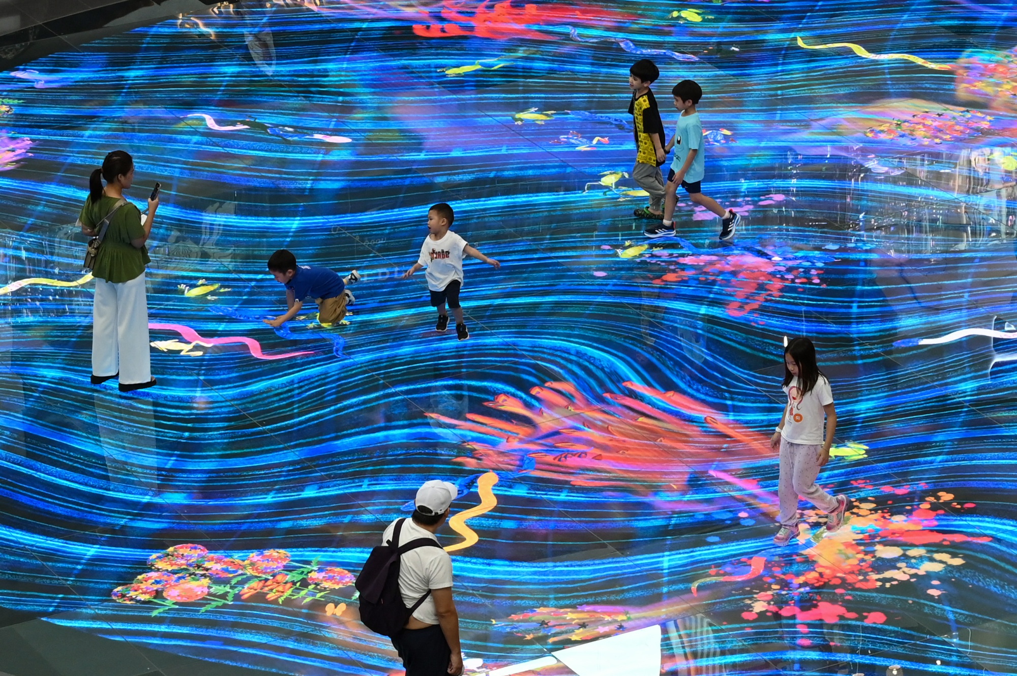 Children play with an interactive projection on the floor at the Marina Bay Sands mall in Singapore on October 27, 2023. (Photo by Roslan RAHMAN / AFP) (Photo by ROSLAN RAHMAN/AFP via Getty Images)