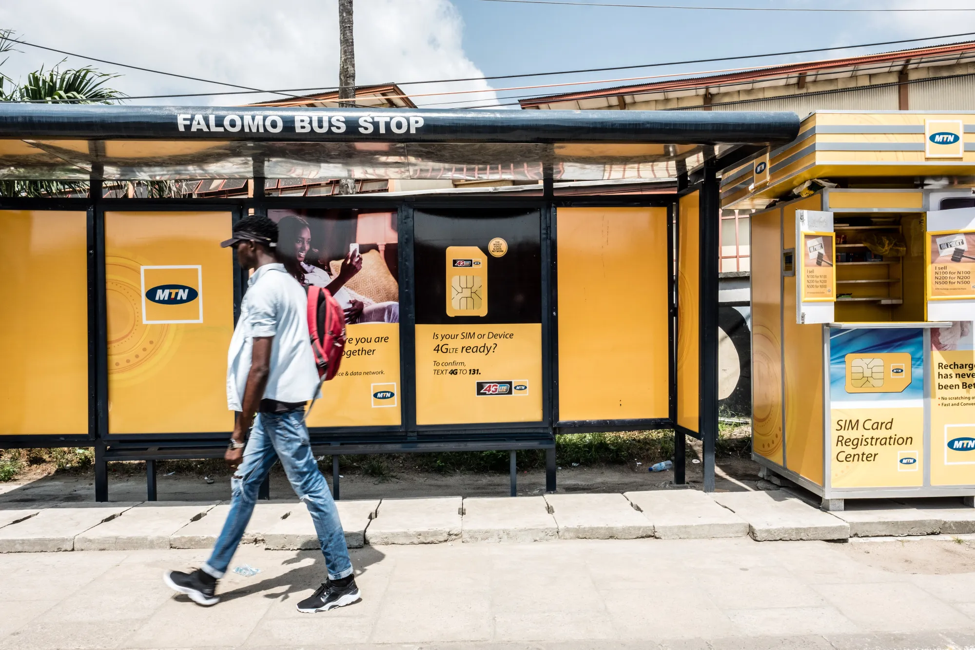 A pedestrian passes by an MTN Group Ltd. bus stop advertisement and roadside kiosk in Lagos, Nigeria, on&nbsp;Nov. 13, 2017.&nbsp;