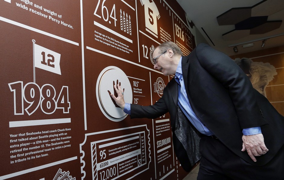 Paul Allen compares his hand size to that of Seahawks quarterback Russell Wilson at an exhibit celebrating the Allen-owned team at Allen's EMP Museum, October 14, 2014.