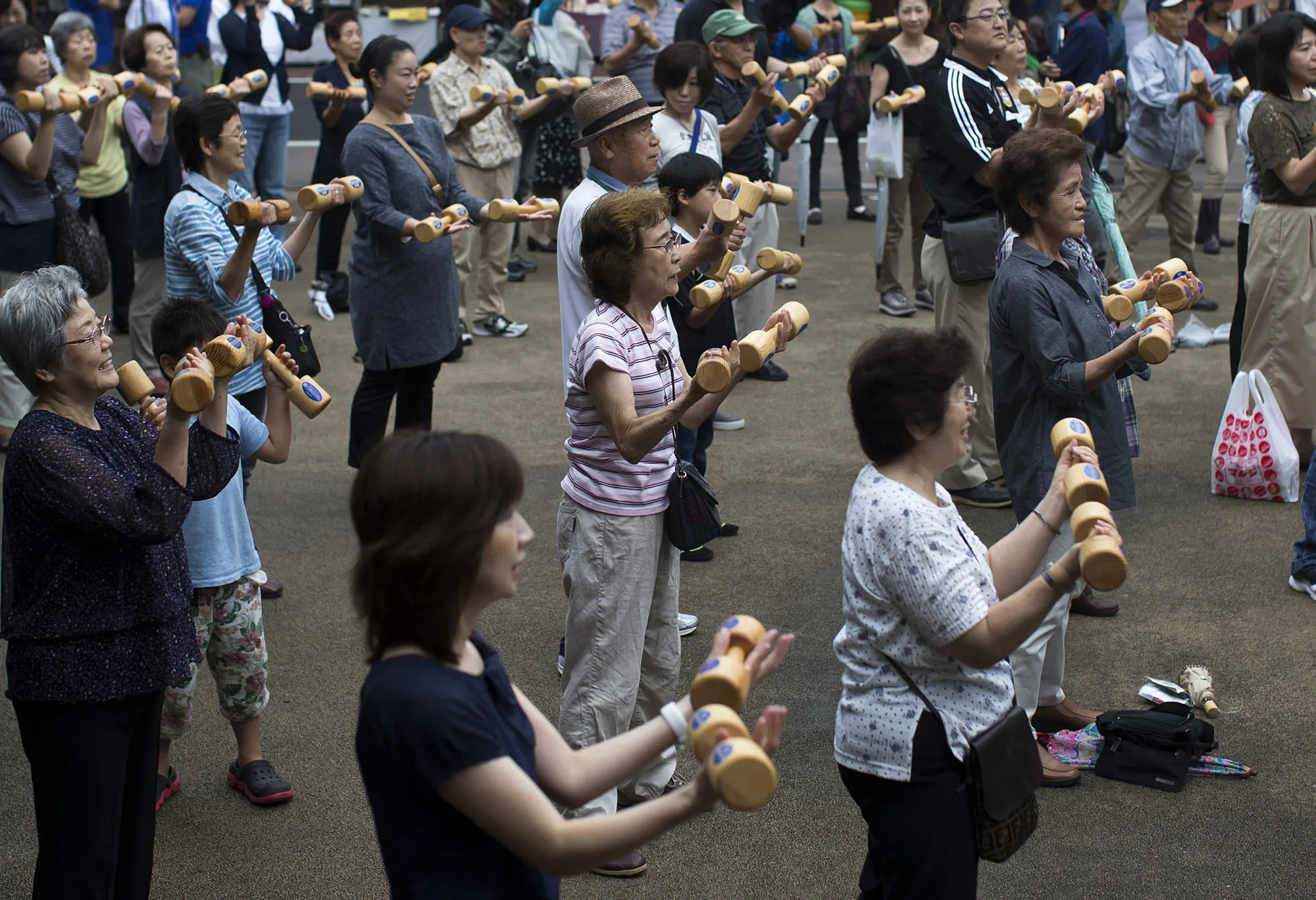 People exercise with wooden dumbbells during an event marking Respect for the Aged Day at a temple in the Sugamo district of Tokyo, Japan, on Monday, Sept. 19, 2016.