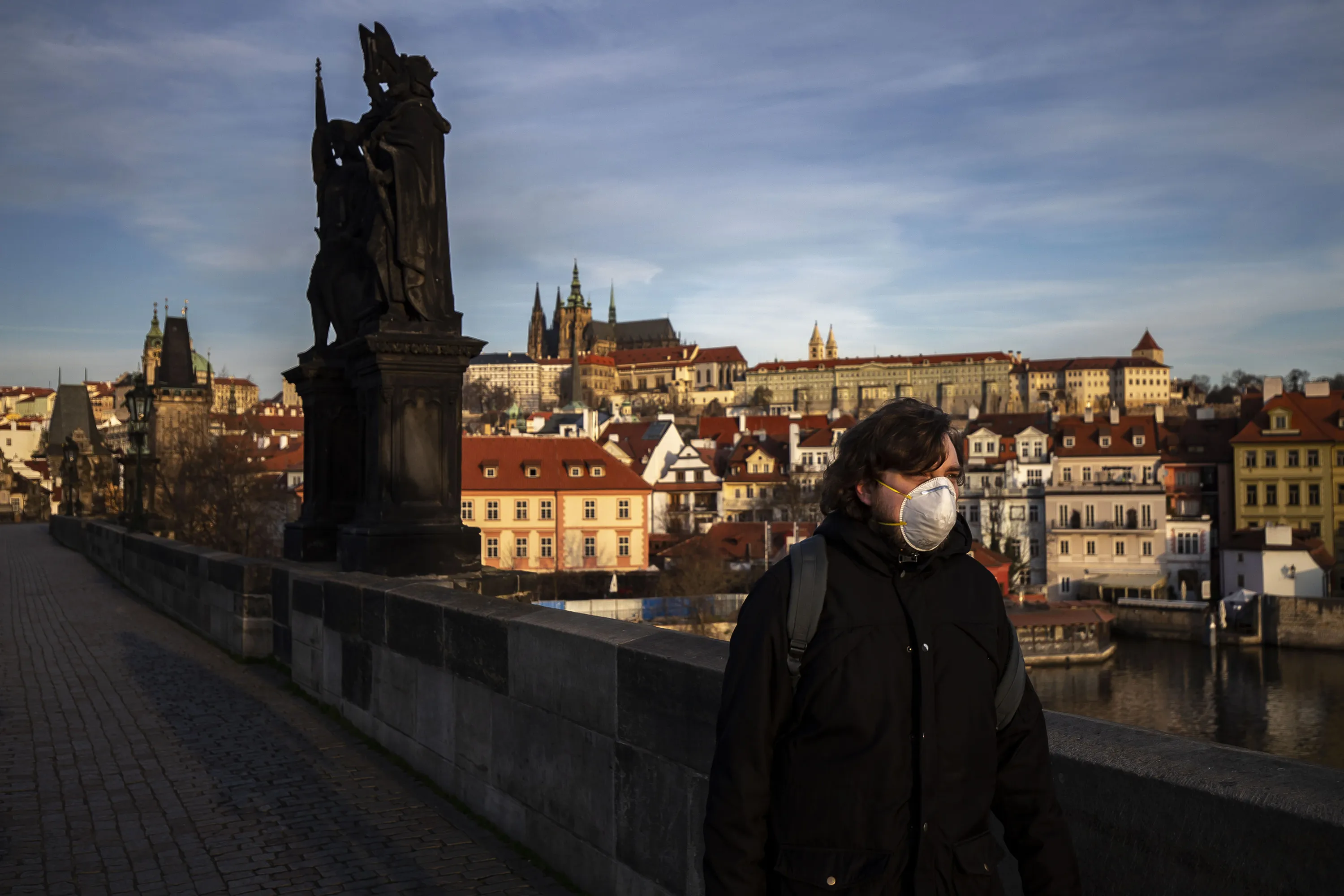 A pedestrian wearing a face mask walks across an empty Charles Bridge in Prague, on March 16.