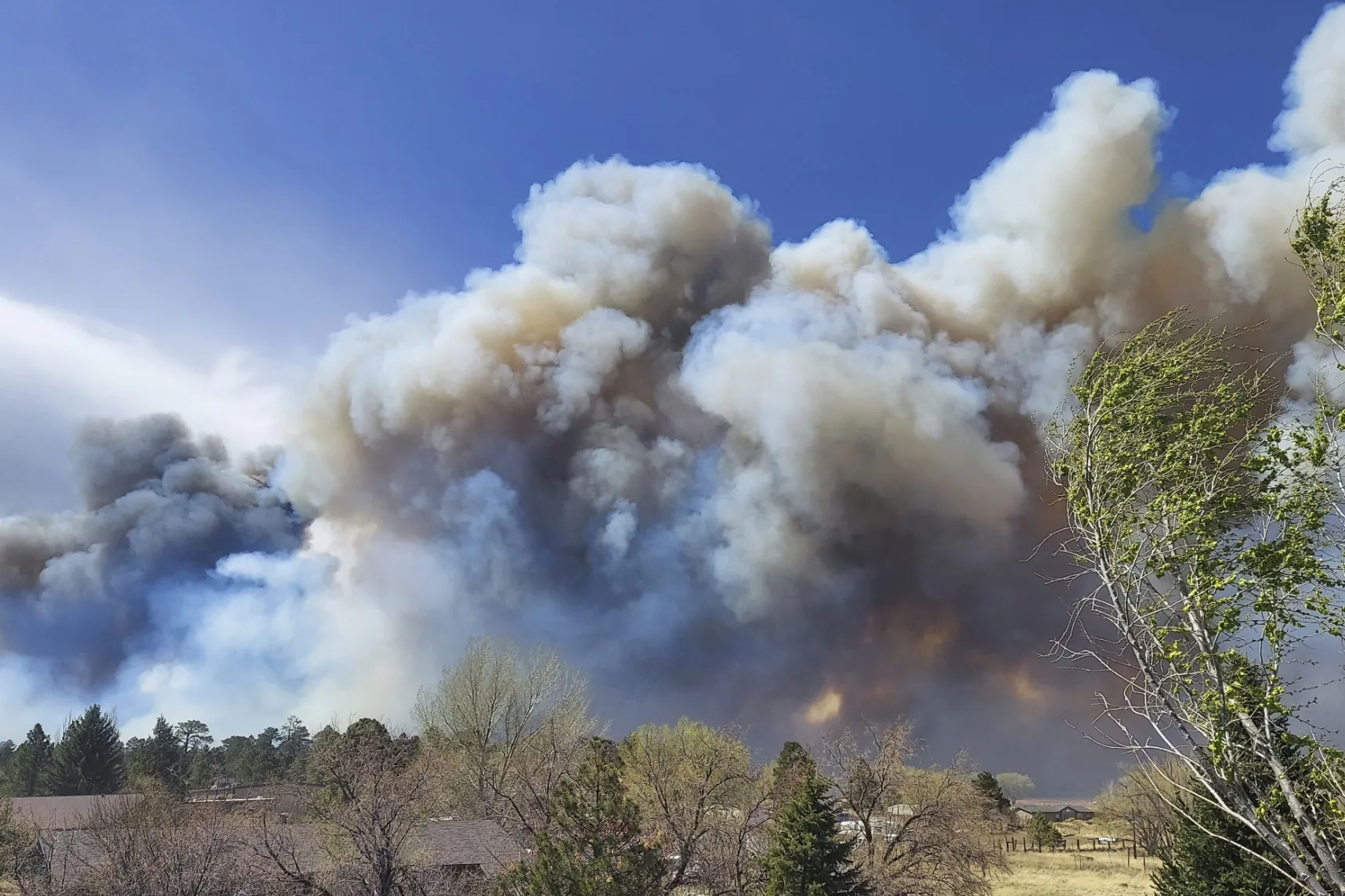 Smoke from a wind-whipped wildfire rises above neighborhoods on the outskirts of Flagstaff, Ariz., on Tuesday, April 19, 2022. (Photographer: Sean Golightly/Arizona Daily Sun via AP)