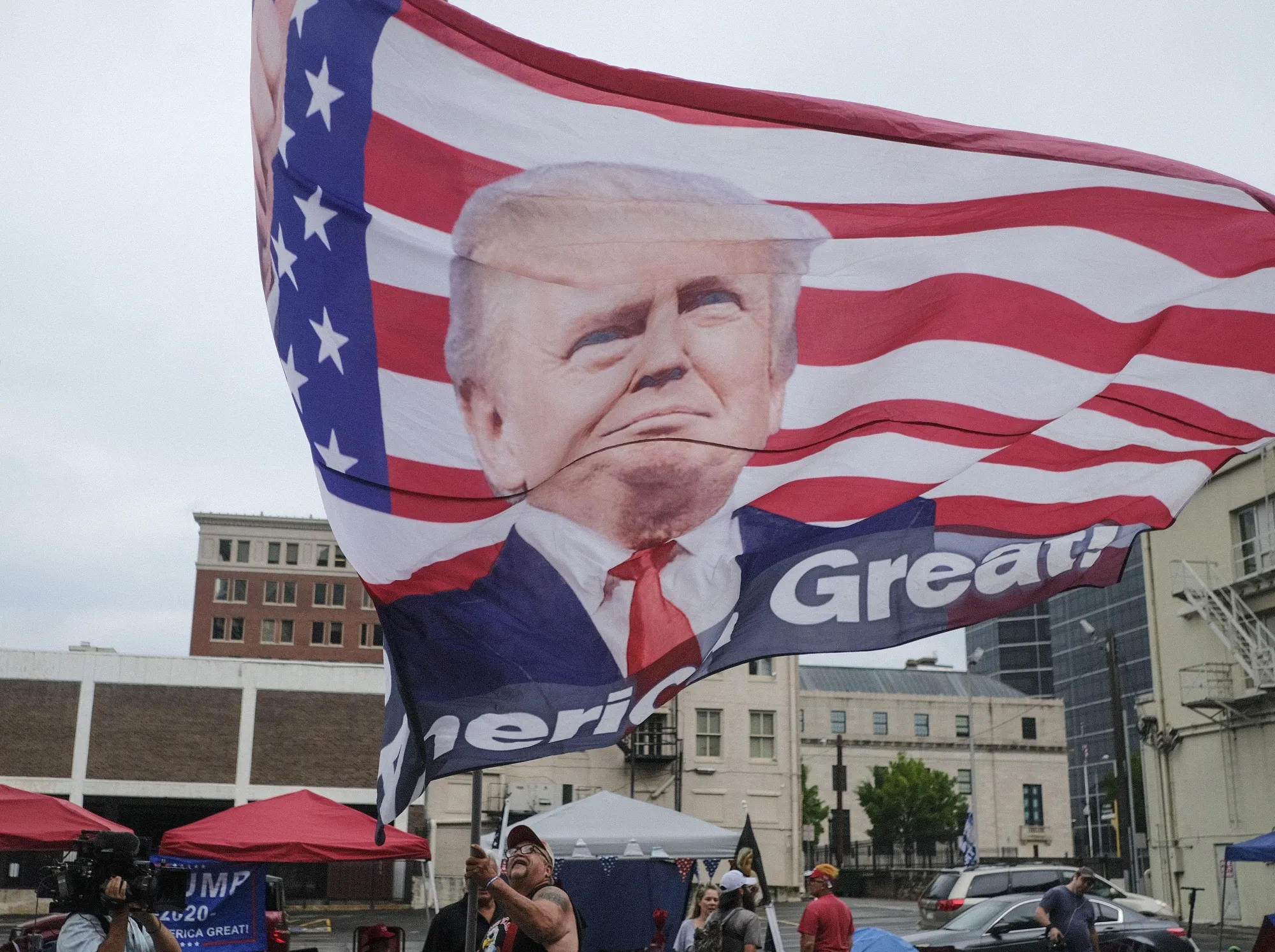 A man parades along the street carrying a flag with the image Donald Trump in Tulsa, Oklahoma on June 19.