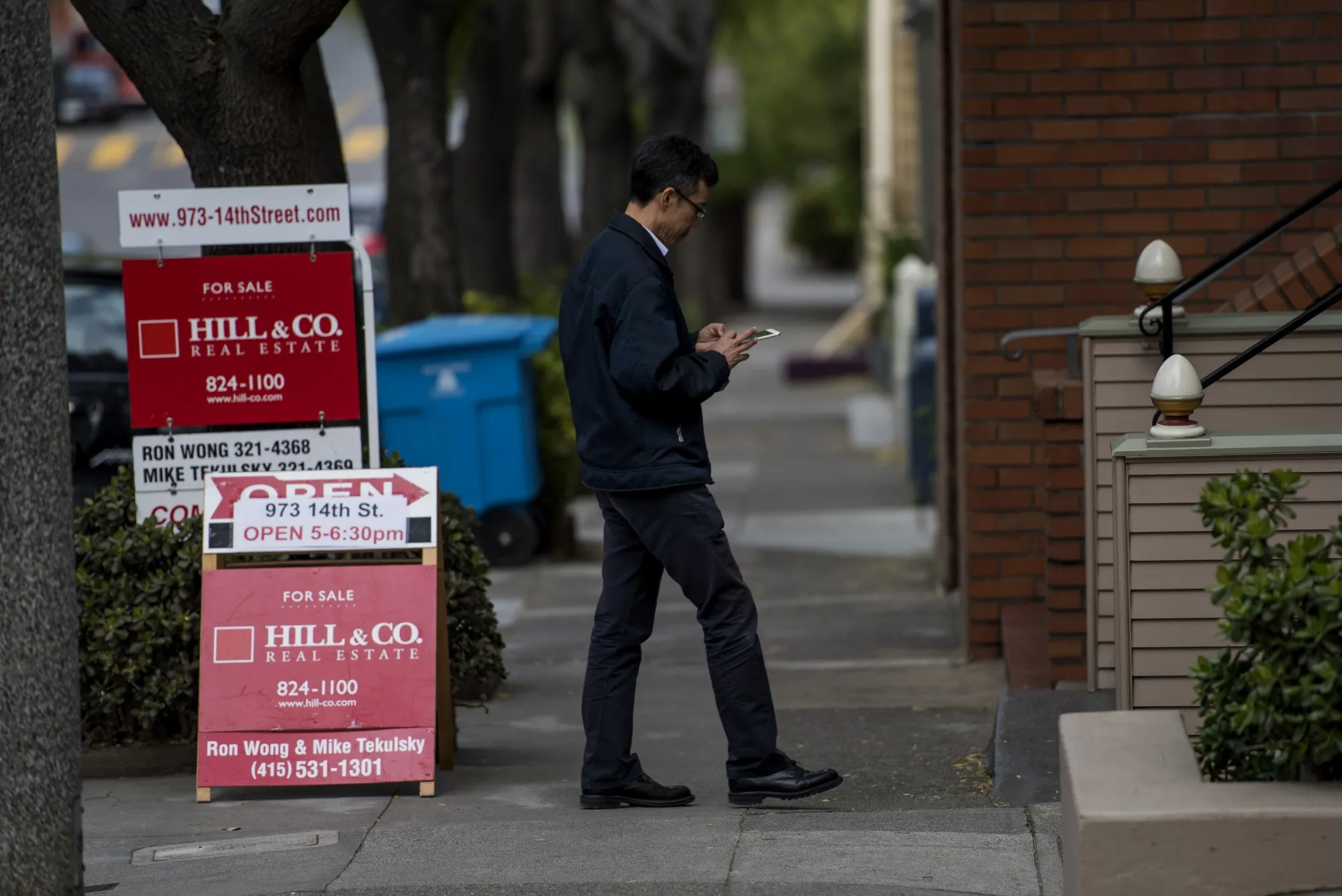 A real estate agent checks his mobile phone while waiting for potential buyers in San Francisco.&nbsp;