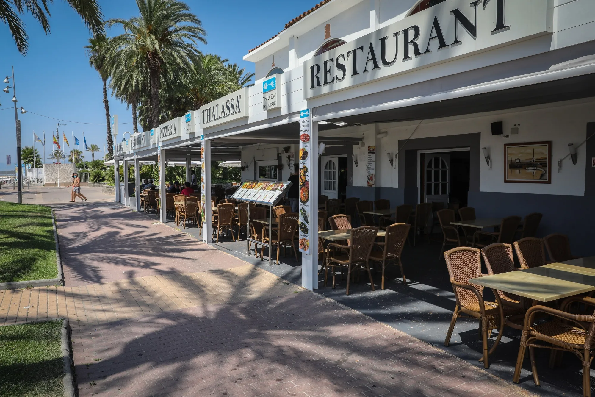 Empty tables sit in the outdoor terrace area of a restaurant by the beach in Salou, Spain.