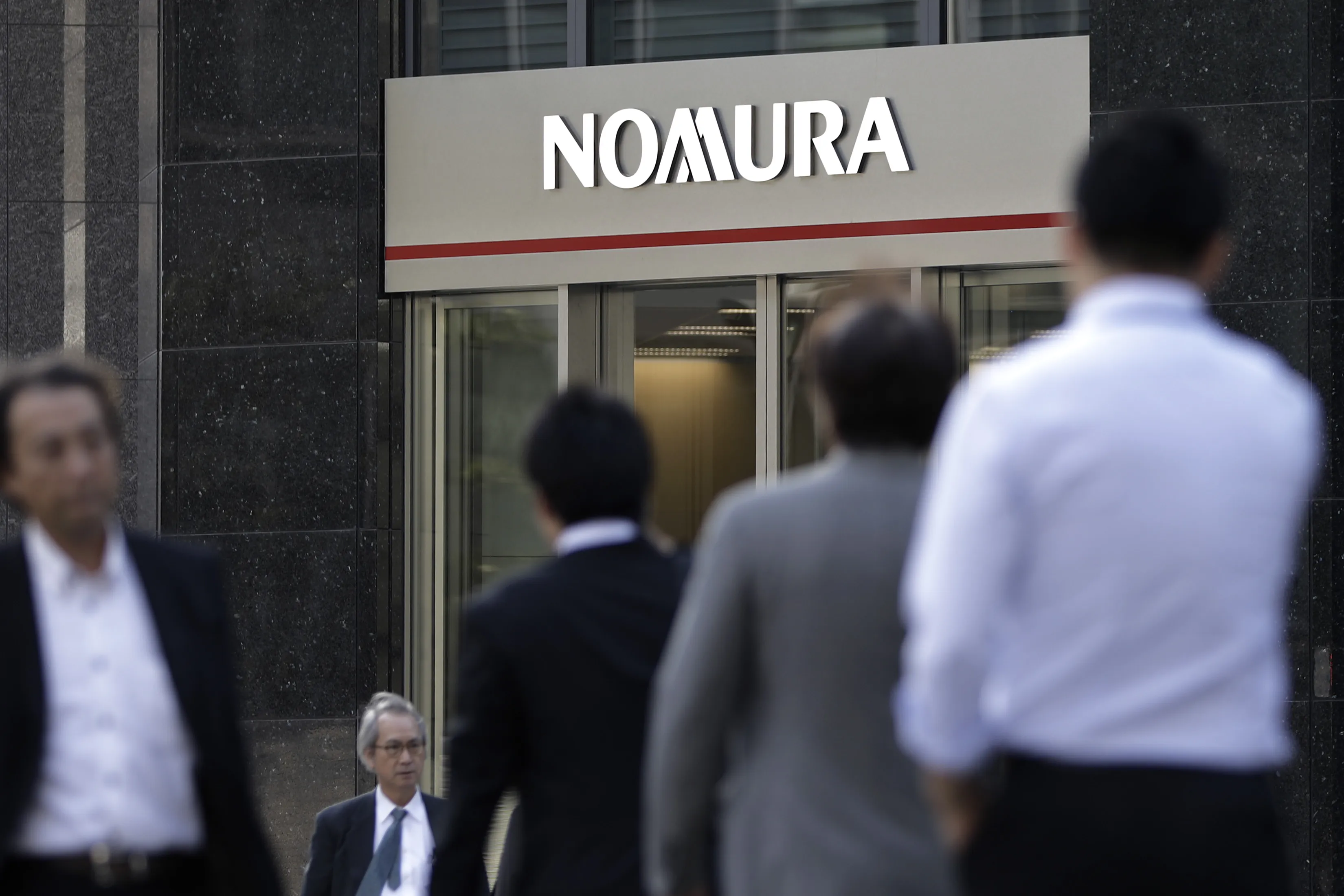 Pedestrians walk past a Nomura branch in Tokyo.