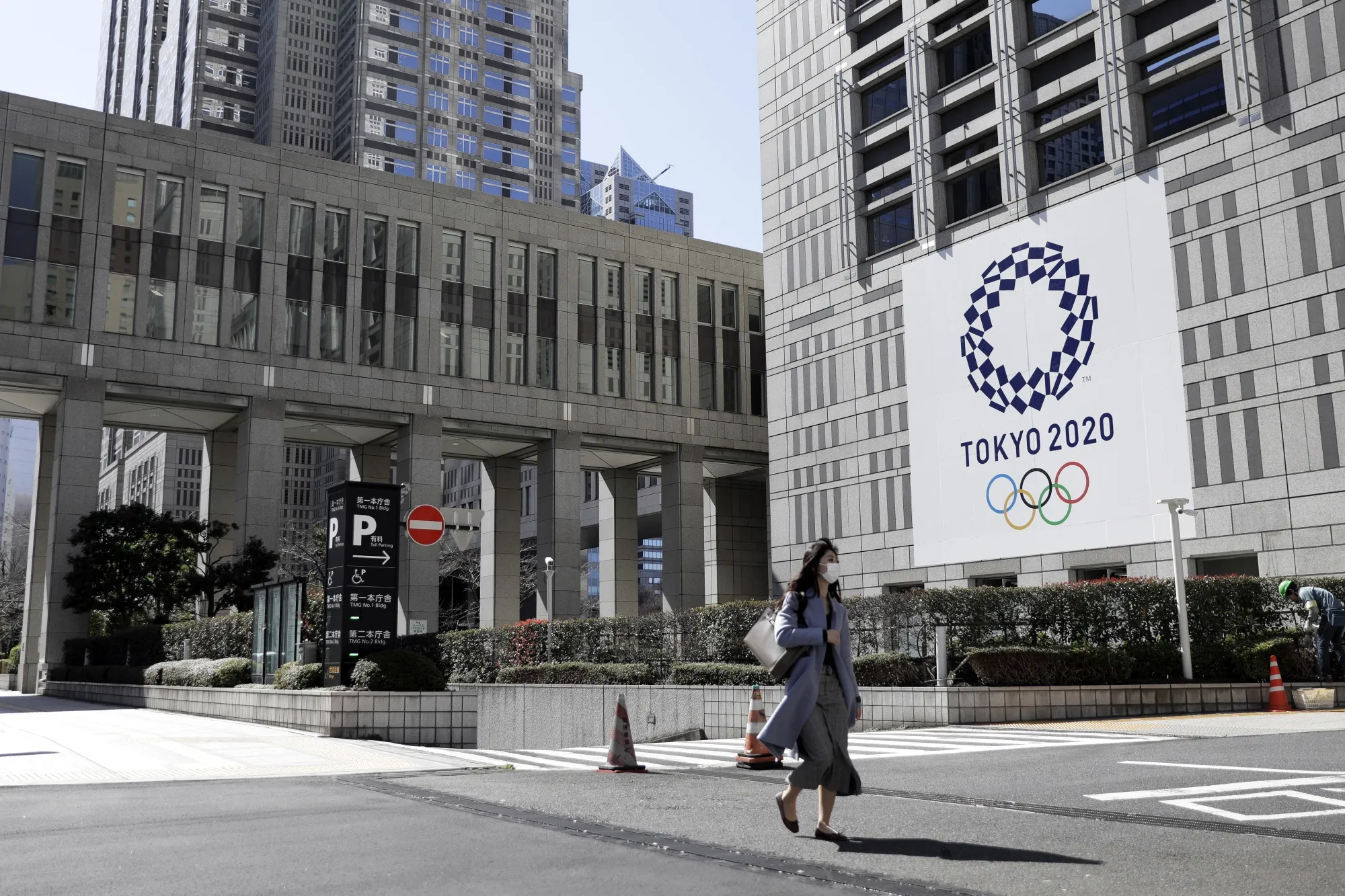 A pedestrian wearing a protective mask walks past a banner featuring the emblem for the Tokyo 2020 Olympic Games in Tokyo, Japan, on&nbsp;March 11.&nbsp;