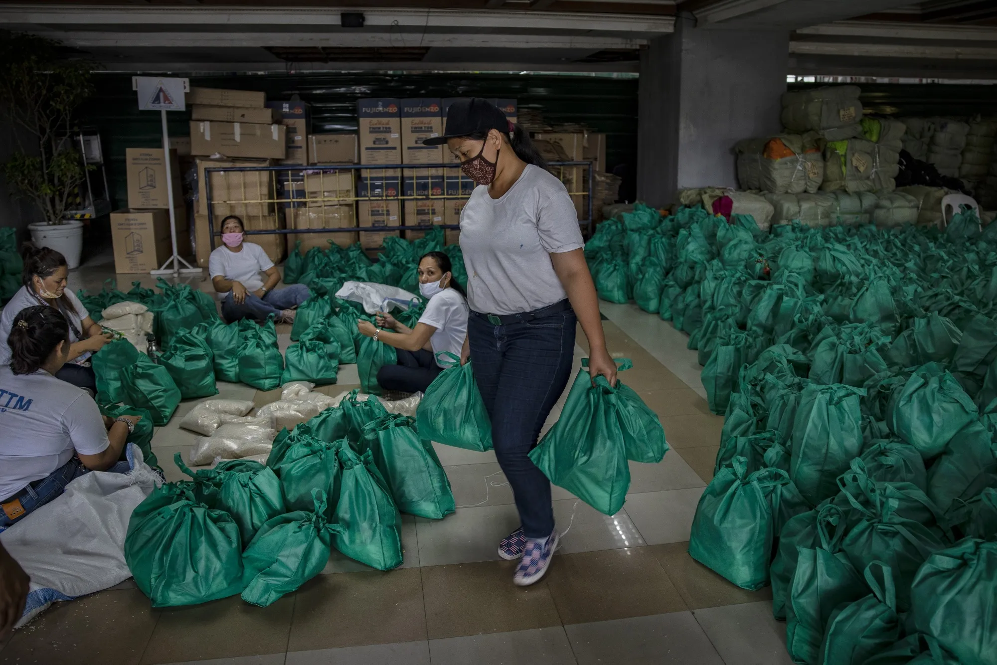 Volunteers pack relief goods for residents running out of food and supplies as they undergo home quarantine in Quezon on March 20.