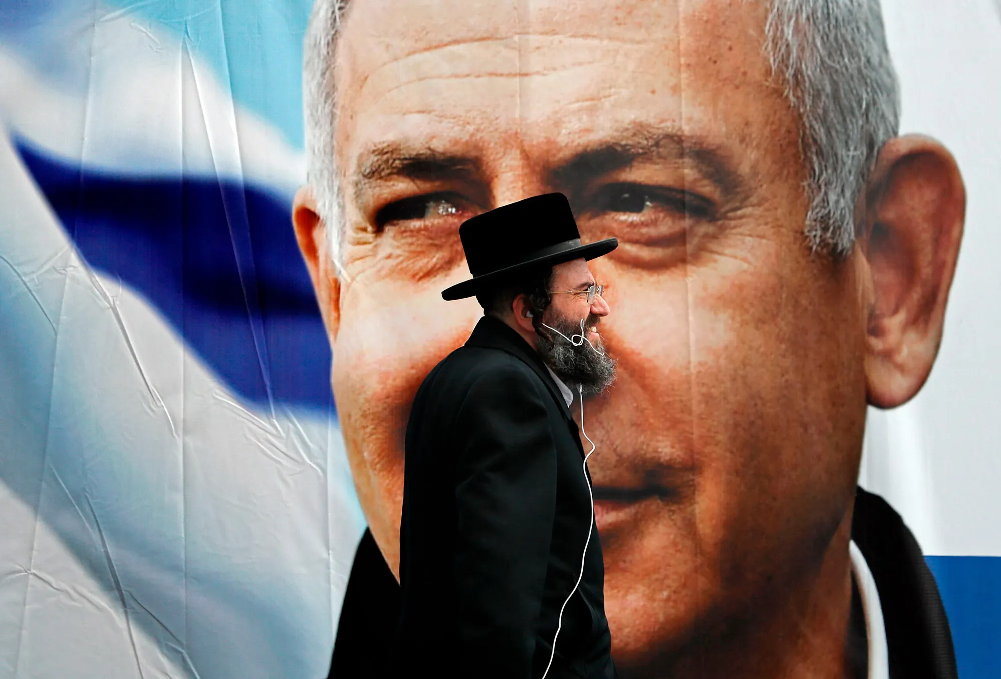 An Ultra Orthodox Jewish man walks past an electoral billboard.&nbsp;