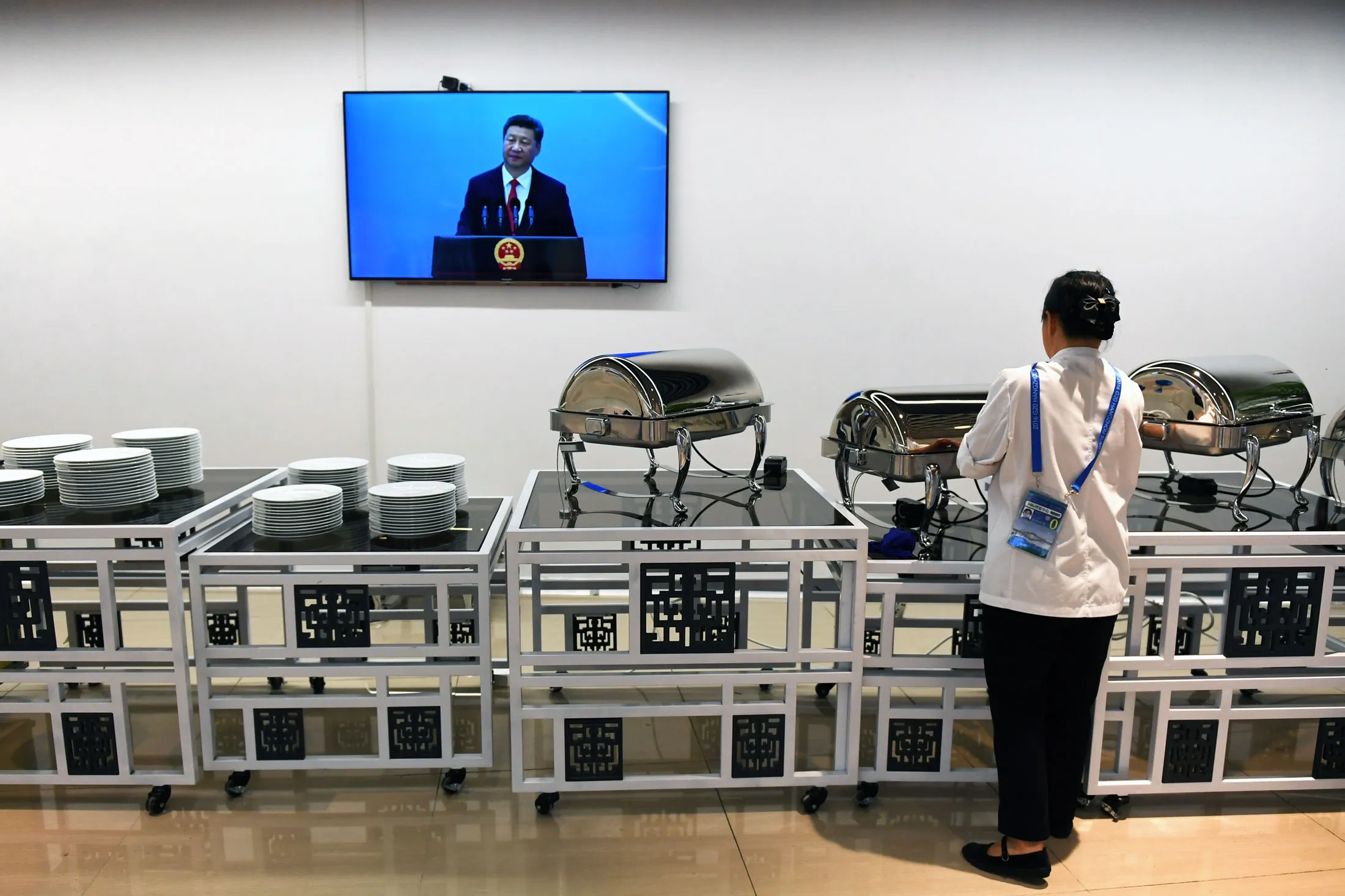 A cleaner watches Chinese President Xi Jinping speak in Hangzhou on Sept. 3.
