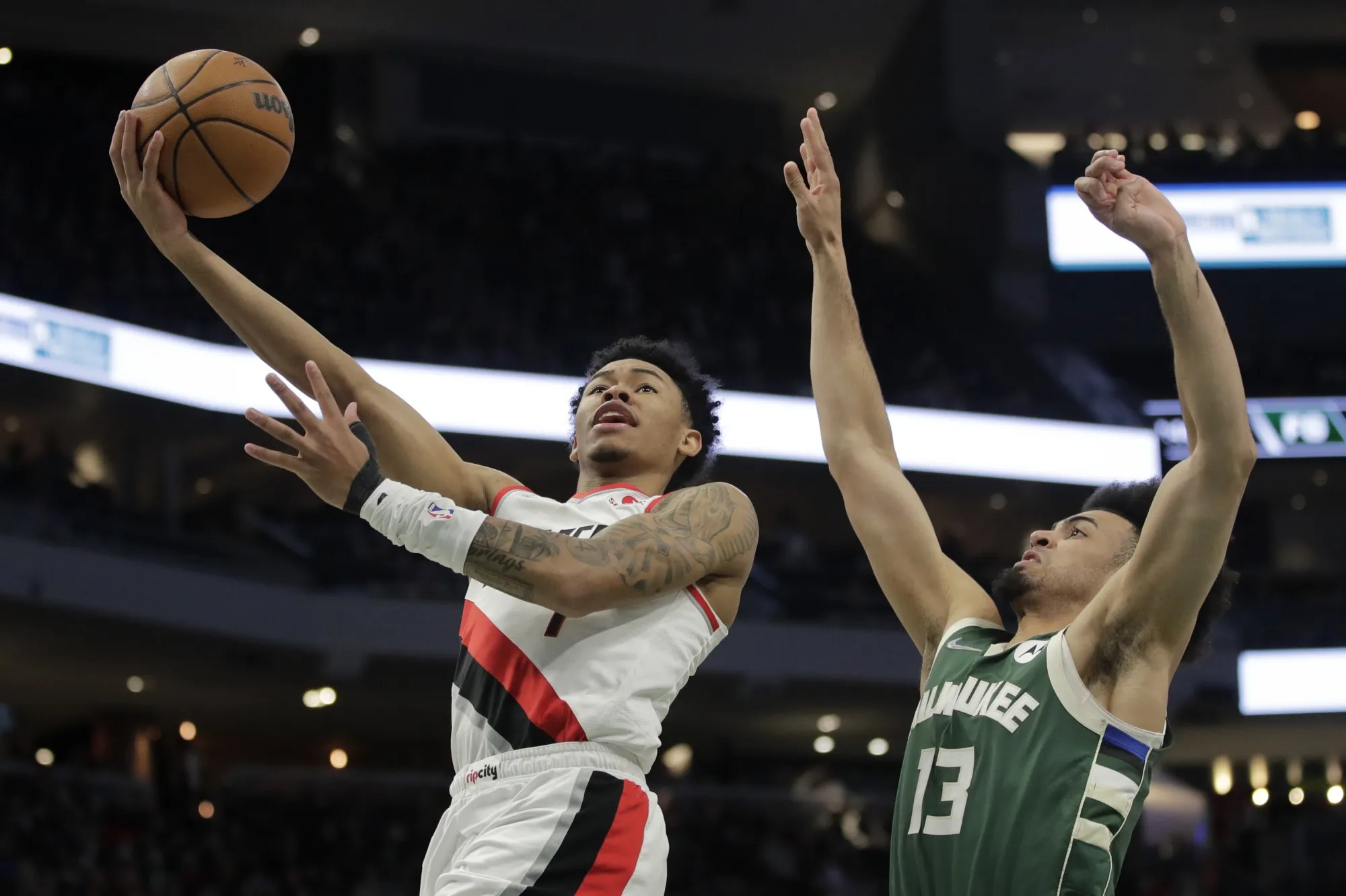 Portland Trail Blazers' Anfernee Simons, left, shoots against Milwaukee Bucks' Jordan Nwora (13) during the first half of an NBA basketball game Monday, Feb. 14, 2022, in Milwaukee. (AP Photo/Aaron Gash)