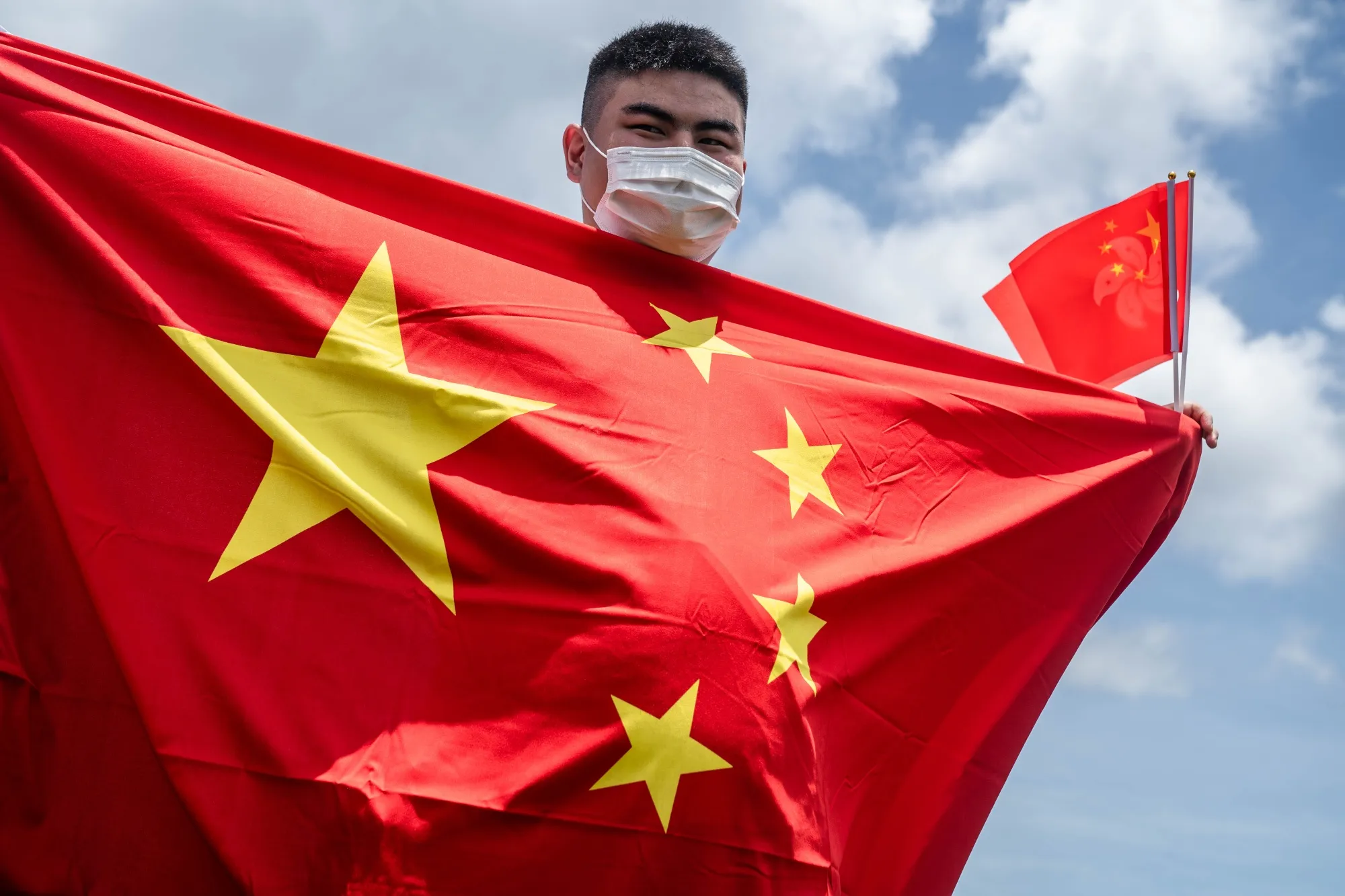 A government supporter&nbsp;holds Chinese and Hong Kong Special Administrative Region (HKSAR) flags to celebrate the passage of a national security law in Hong Kong in 2020.