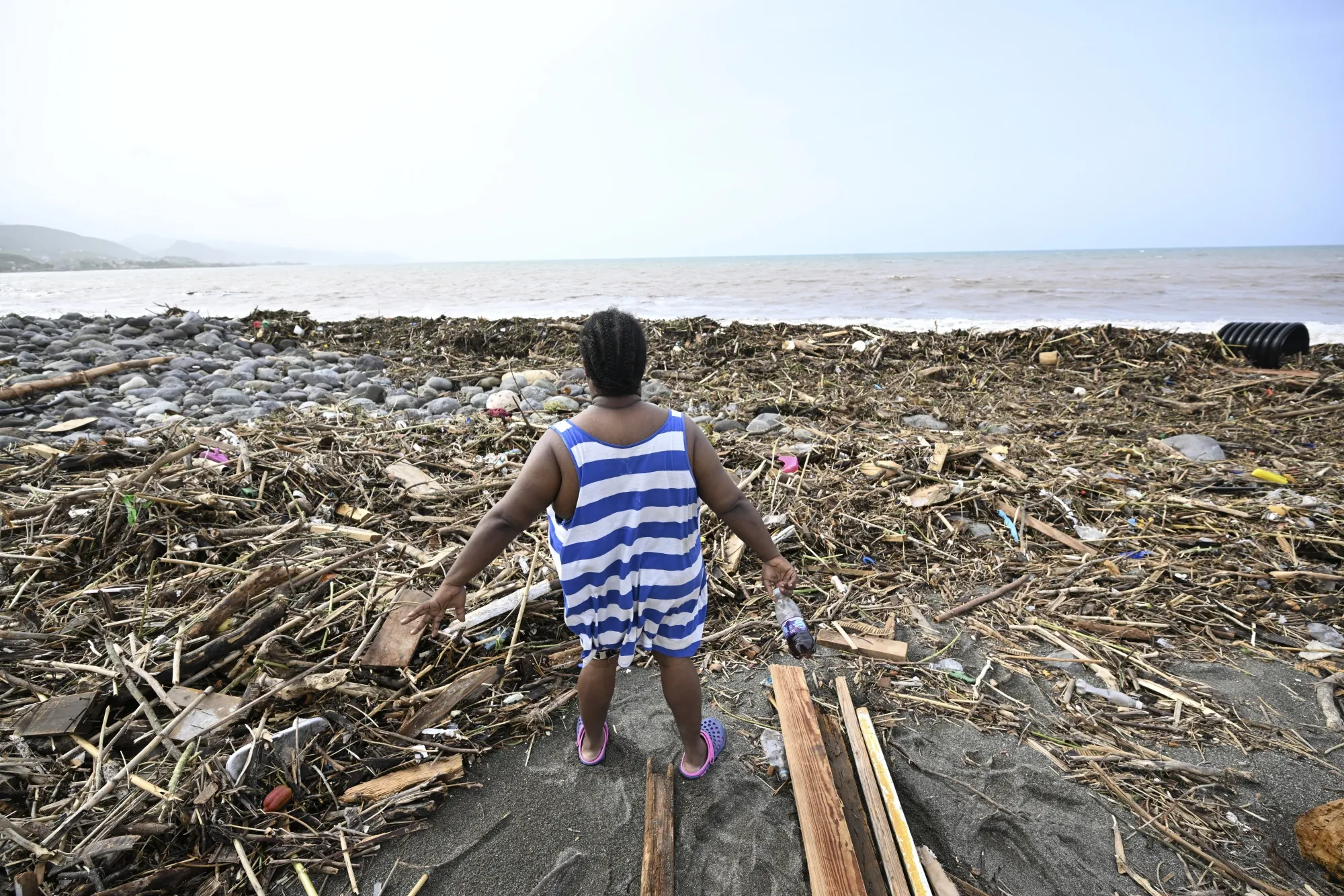 A woman looks at a beach littered with trash in the aftermath of Hurricane Beryl at Bull Bay, Jamaica on July 4.