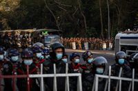 Military soldiers stand behind a line of riot police during a protest in Yangon, on Feb. 9.