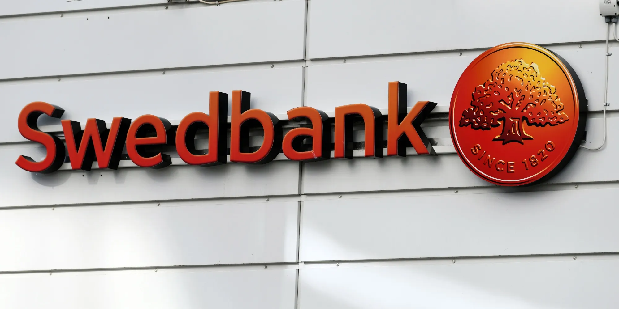 A sign sits on the exterior of the Swedbank AB headquarters in Sundbyberg, Sweden, on Tuesday, March 5, 2019.&nbsp;