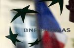 A French national flag is reflected on a plaque at the BNP Paribas SA headquarters in Paris.