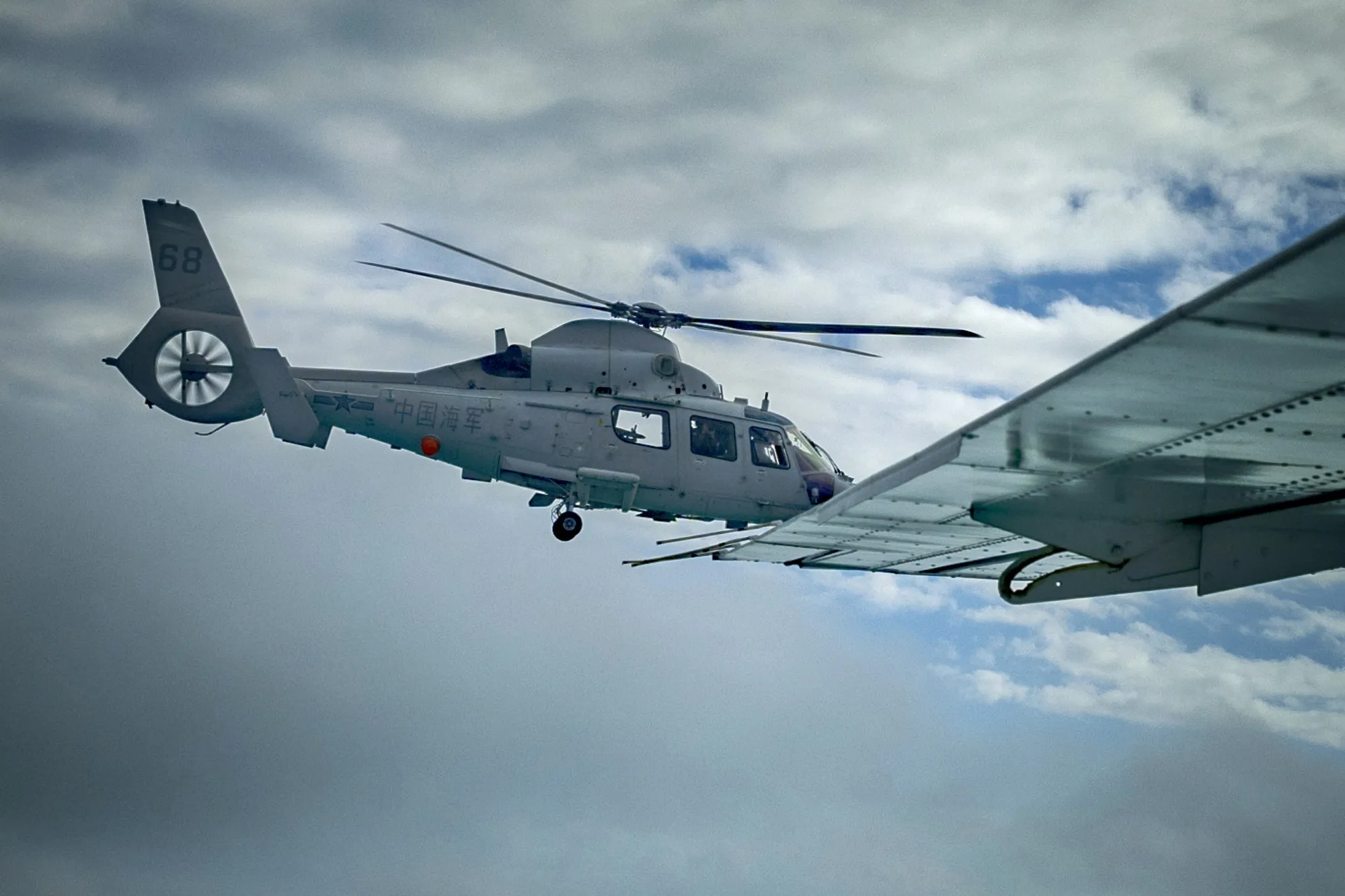 A Chinese Navy helicopter flies close to a Philippine Bureau of Fisheries and Aquatic Resources plane above Scarborough Shoal on Feb. 18.