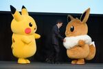 Tsunekazu Ishihara, chief executive officer of Pokemon Co., appears on the stage with Pokomon characters Pikachu, left, and Eevee.