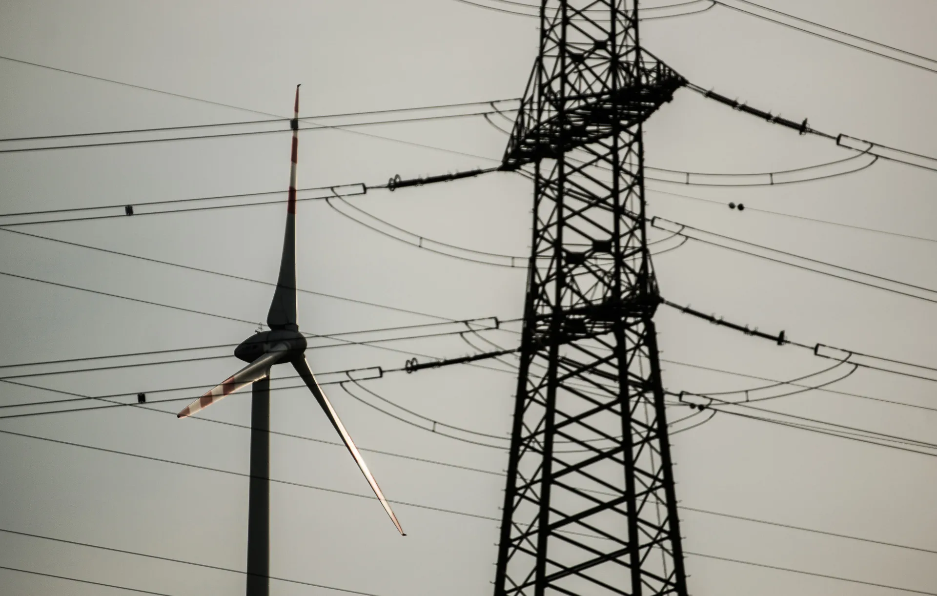 A wind turbine stands beyond power transmission lines&nbsp;in Nickelsdorf, Austria.