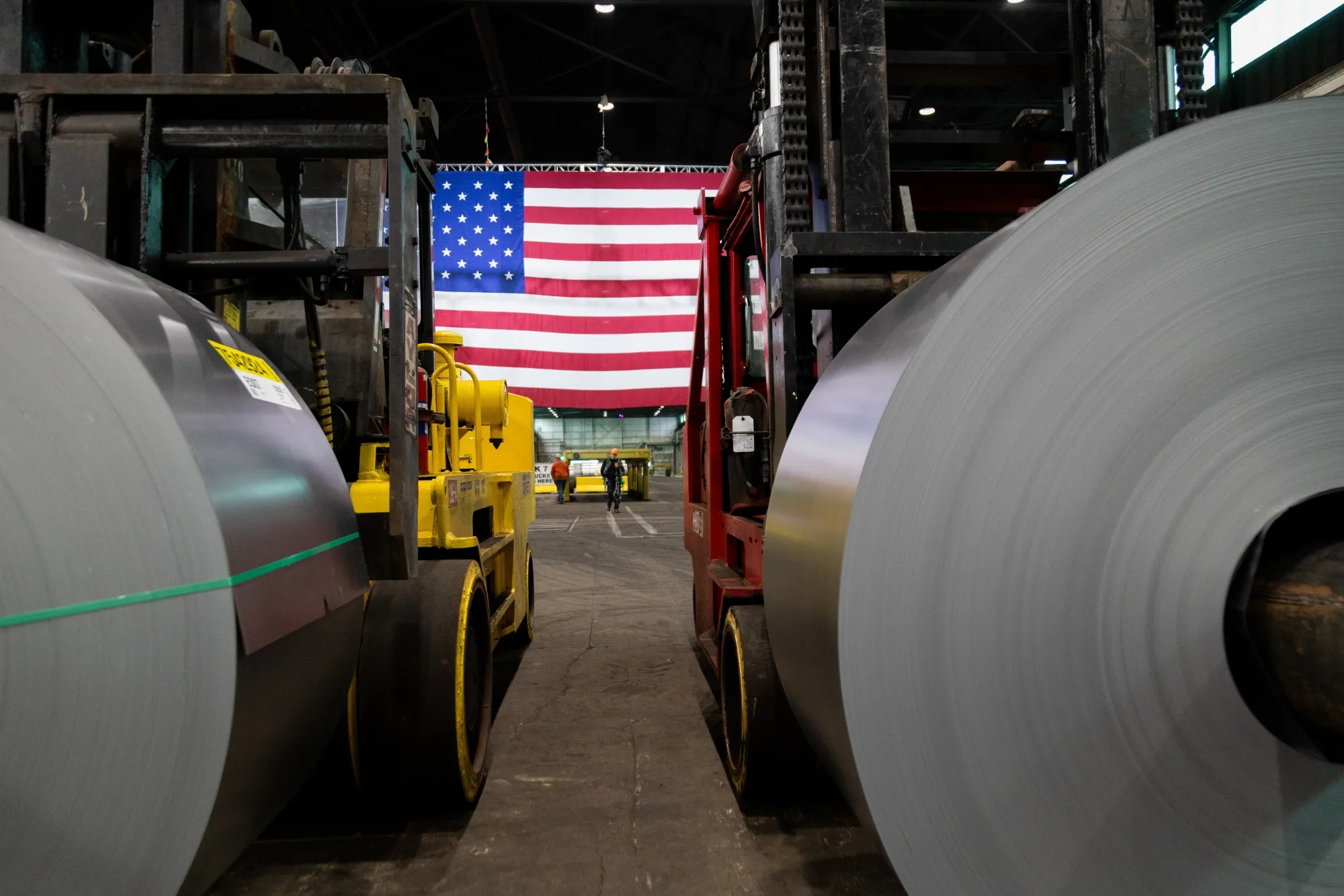 Steel coils in front of a US flag at the US Steel Corporation Irvin Works facility in West Mifflin, Pennsylvania.
