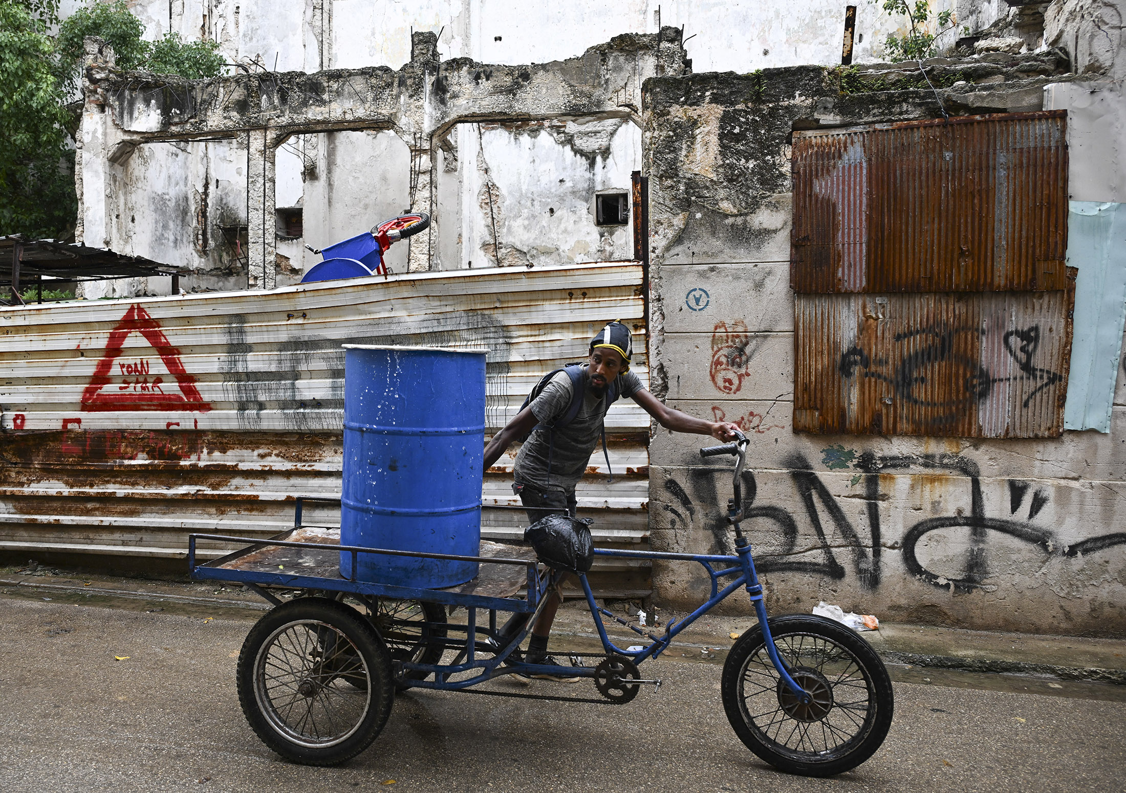 A man transports a water tank on a tricycle during a power outage in Havana on June 10, 2026. Photographer: Yamil Lage/AFP/Getty Images