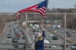 A demonstrator waves an American flag as trucks drive southbound on I-495 while circling the Washington Beltway in Bethesda, Maryland, on March 6.