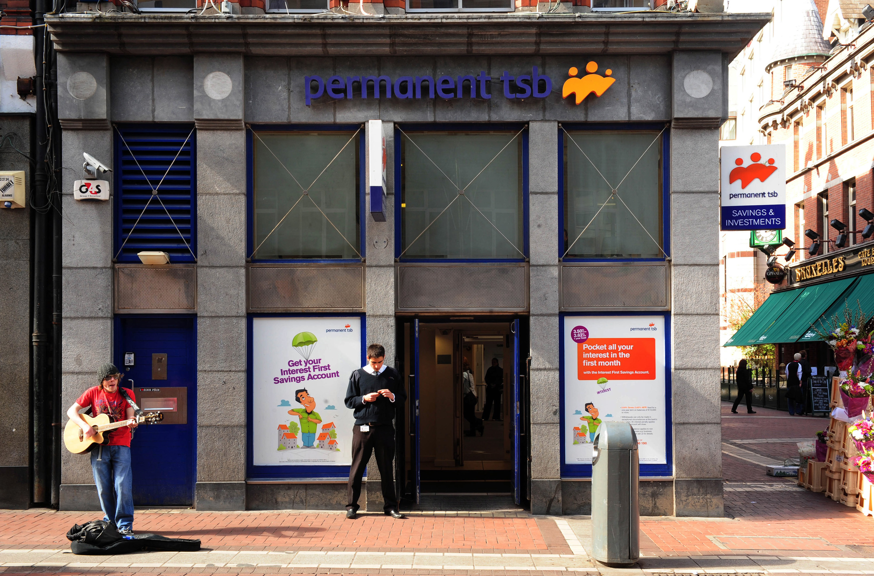 A Busker Stands Outside a Branch of the Permanent TSB in Dublin
