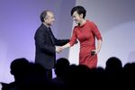 Masayoshi Son, chairman and chief executive officer of SoftBank Group Corp., left, shakes hands with Jean Liu, president of Didi Chuxing.