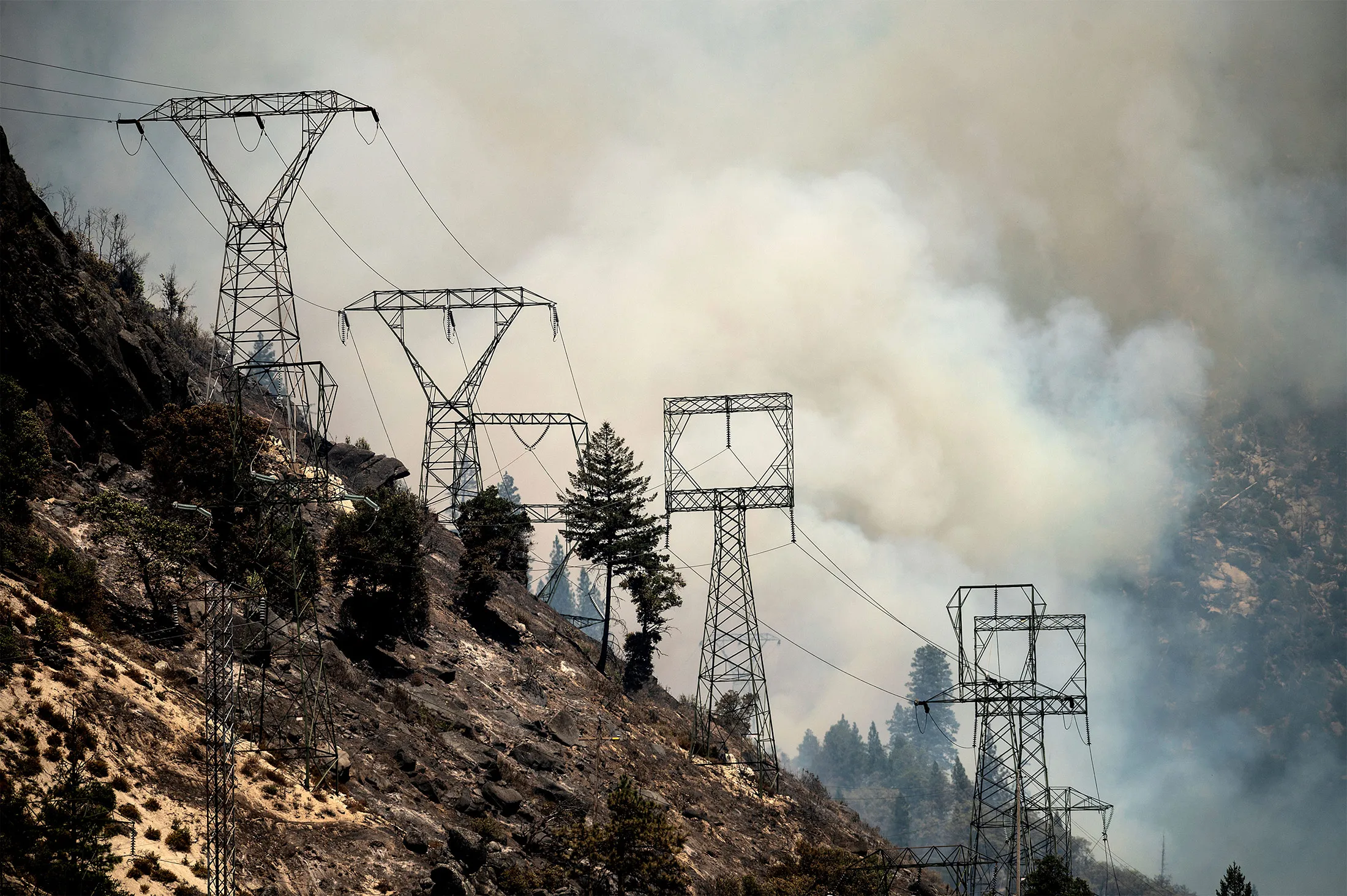 Smoke billows behind power lines as the Dixie Fire burns along Highway 70 in Plumas National Forest, Calif., on&nbsp;July 16.&nbsp;