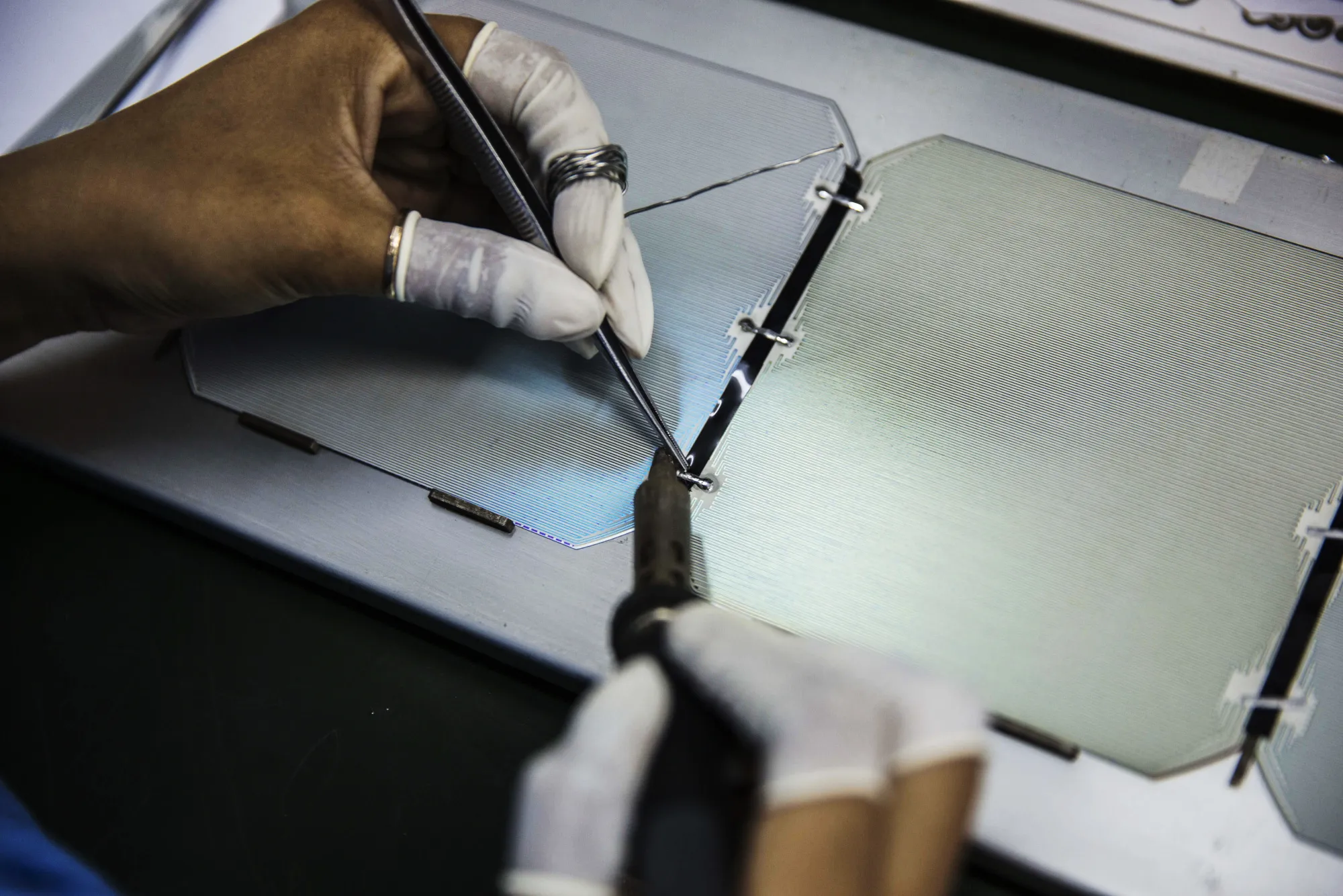 A worker solders solar cell modules at a factory in Cambodia.