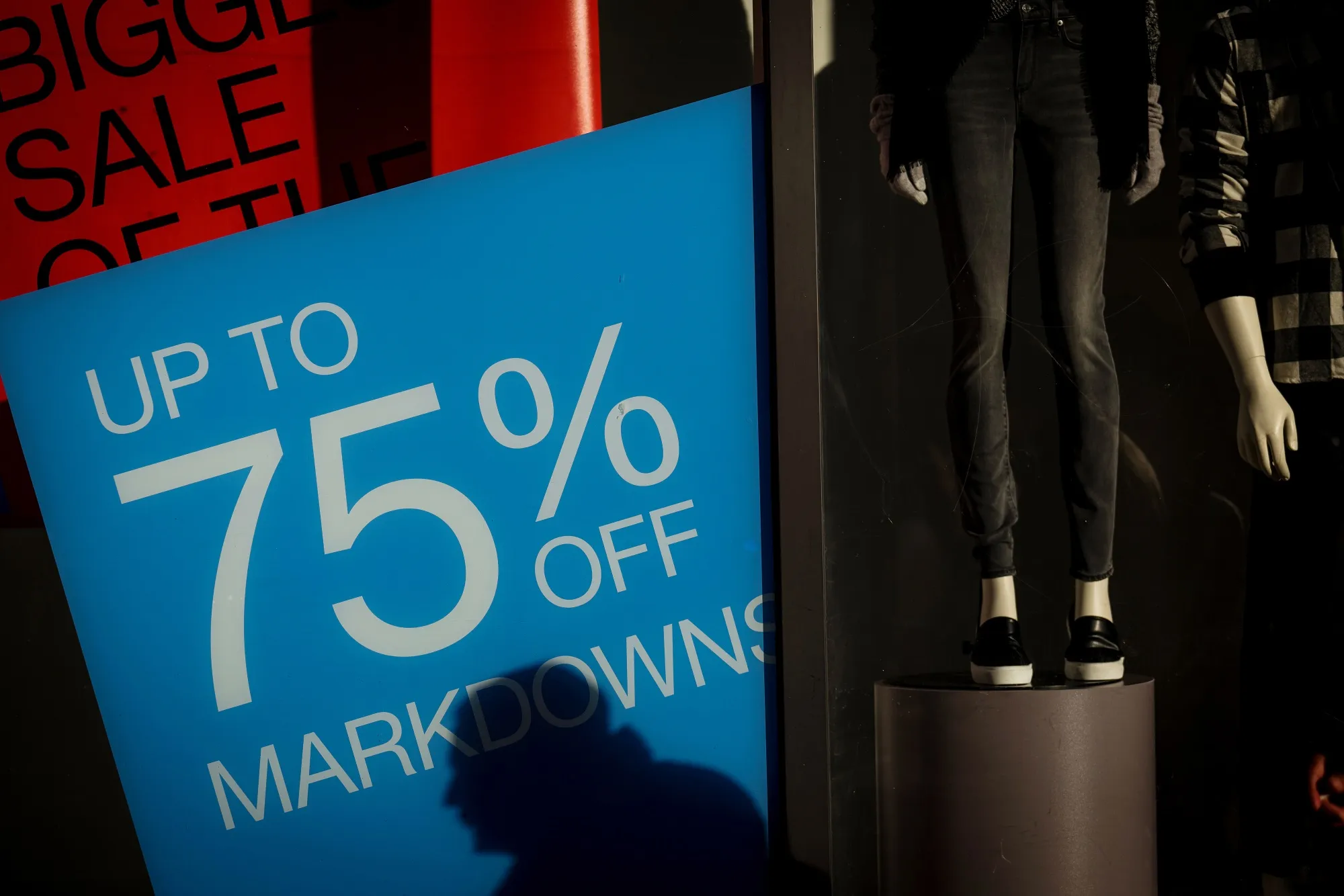 The shadow of a pedestrian is cast on a sale sign at a store&nbsp;in San Francisco.