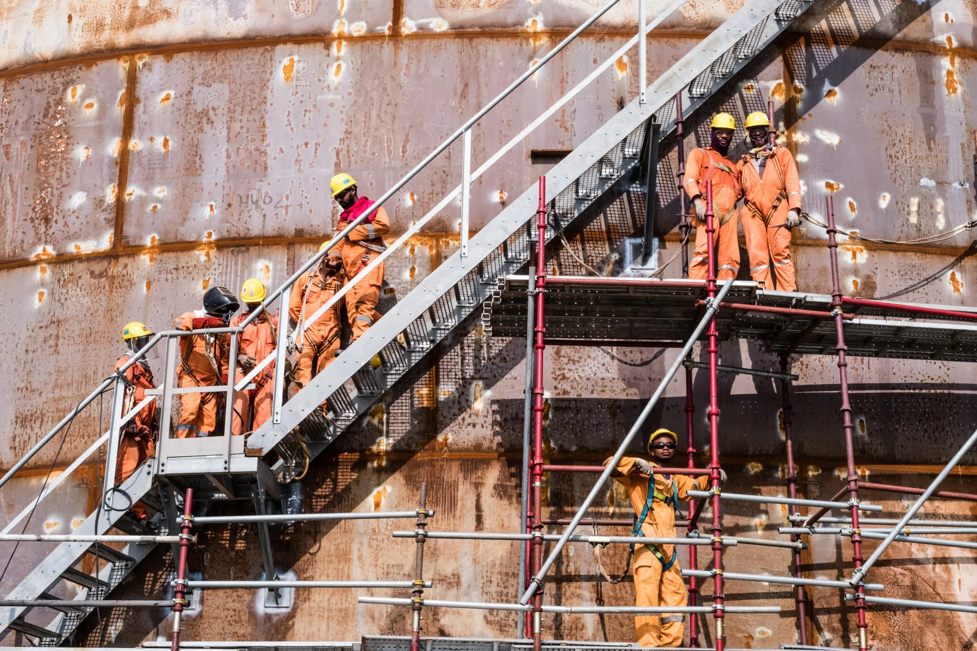 Workers climb scaffolding surrounding a storage tank at an oil refinery in the Ibeju Lekki district, outside of Lagos, Nigeria in 2018.