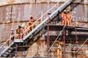 Workers climb scaffolding surrounding a storage tank at an oil refinery in the Ibeju Lekki district, outside of Lagos, Nigeria in 2018.